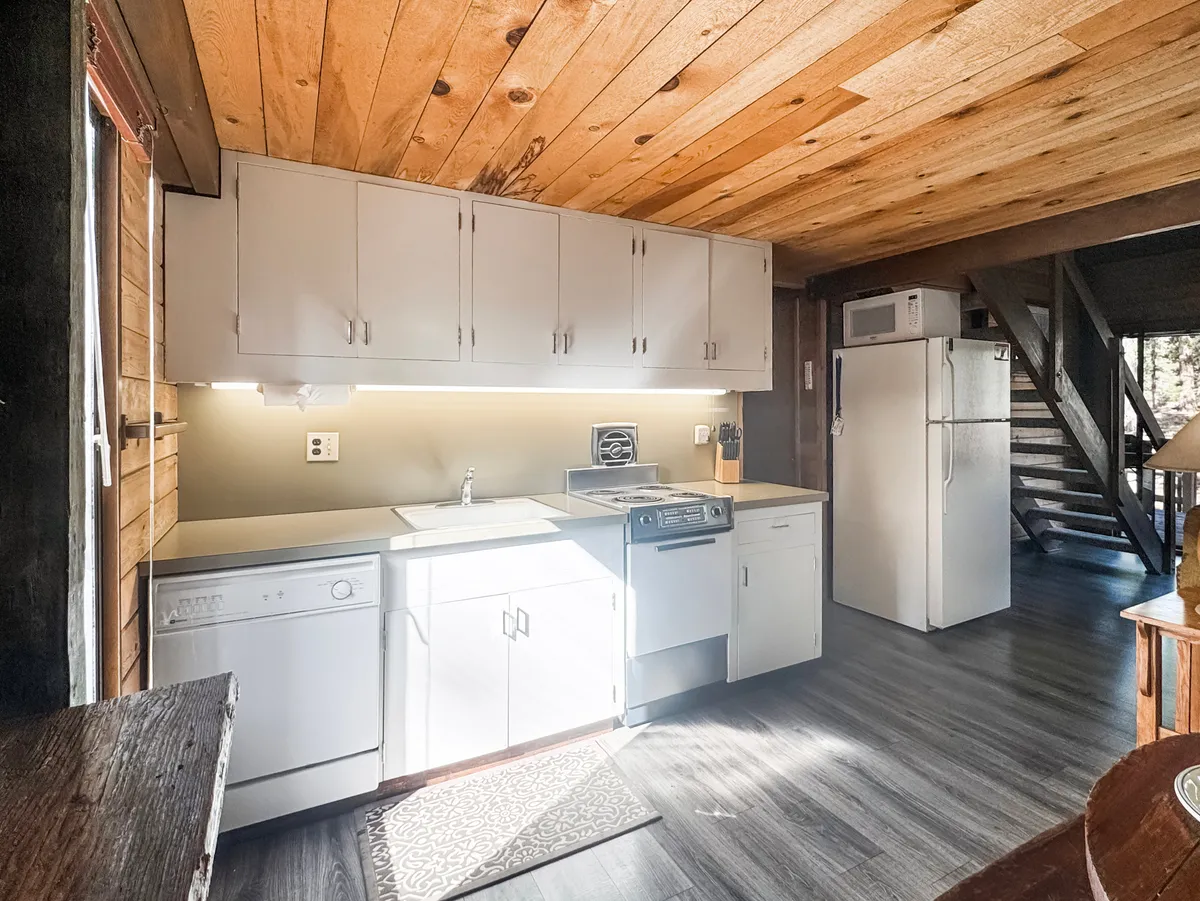A cozy kitchenette with a wooden ceiling and modern stainless steel appliances. The space is designed for cooking and socializing, inviting family members to prepare meals together and enjoy quality time in the kitchen.